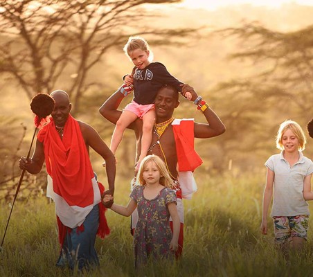 three tourists children walking with two masai locals through the bush an amazing learning life experience on a beautiful holiday in Africa