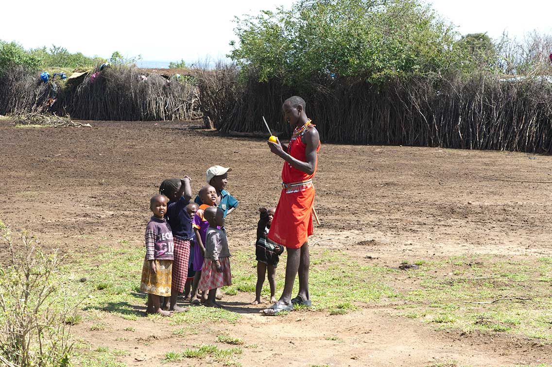 maasai mana cuts orange for kids in his boma meet the maasai on safari ®bushtreksafaris