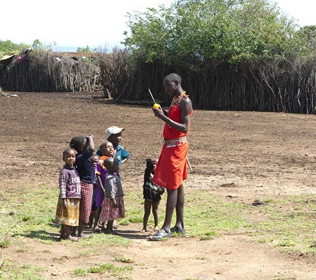 maasai mana cuts orange for kids in his boma meet the maasai on safari ®bushtreksafaris